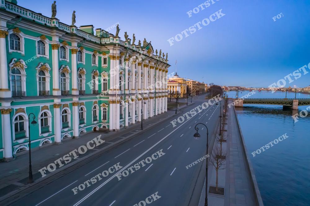 На фотографии изображён Зимний дворец, являющийся частью комплекса Эрмитажа, расположенный на Дворцовой набережной. Пустая улица подчёркивает утреннюю тишину Санкт-Петербурга. На заднем плане виден мост через реку Неву и её зеркальная гладь. Архитектура дворца и окружающий городской пейзаж создают атмосферу величия и гармонии.